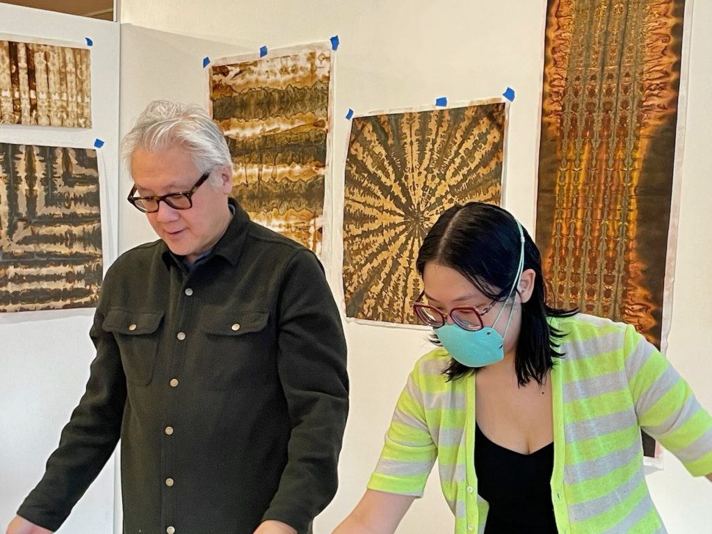 Larry Lee and Mari Miller looking down at prints on a table, though the table is not visible