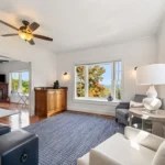 Bright living room with large window, blue rug, white walls, and modern furniture.