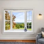 Large window overlooking a green landscape and autumn trees.