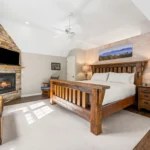 Cozy bedroom with a large bed, fireplace, and beamed ceiling.