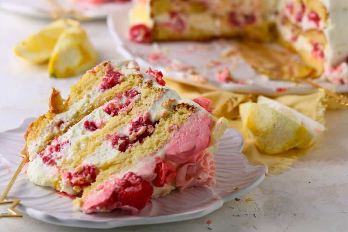 Slice of keto raspberry lemon cake layered with lemon cream and raspberries.