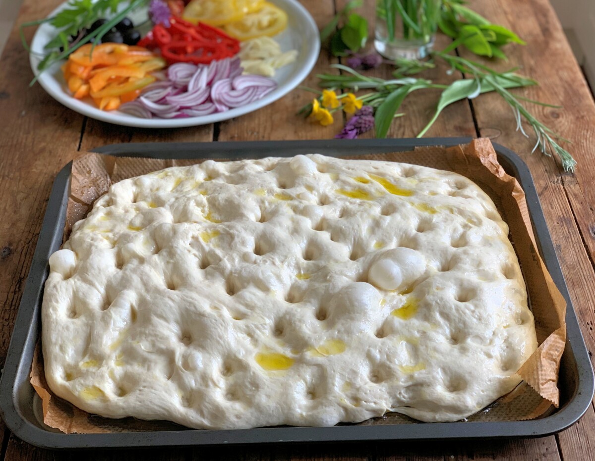 Pre-heat the oven to 220C (Fan 200C)/450F/Gas mark 7.
Once the dough has almost doubled in size, gently pull it to fill the baking tray if necessary and make dimples in the dough using your fingertips.
Drizzle over more olive oil and press the garlic slices into the dimples.