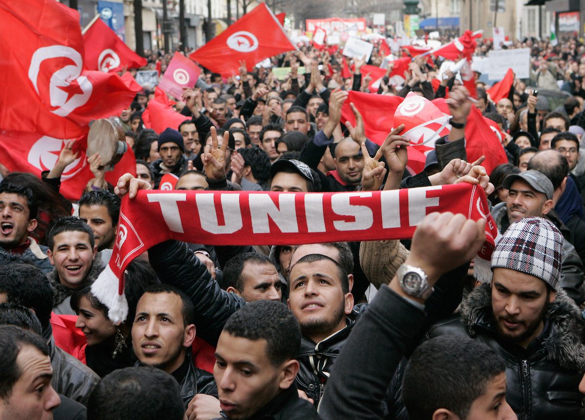 Espatriati tunisini gridano slogan mentre tengono in mano bandiere tunisine mentre manifestano il 15 gennaio 2011 a Parigi, Francia.  [Franck Prevel/Getty Images]