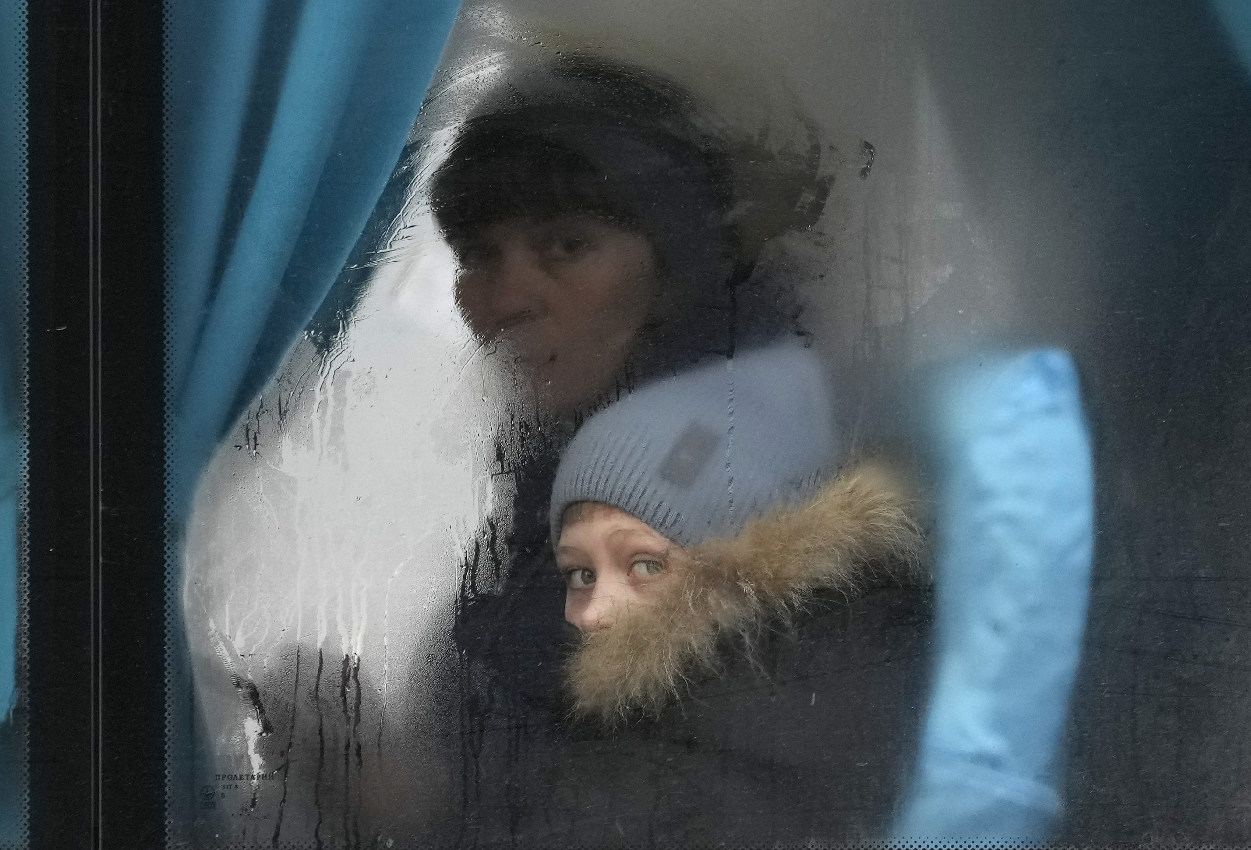 Una mujer y un niño miran por la ventana de un autobús mientras salen de Sievierodonetsk, en la región de Luhansk, en el este de Ucrania, el jueves 24 de febrero de 2022.