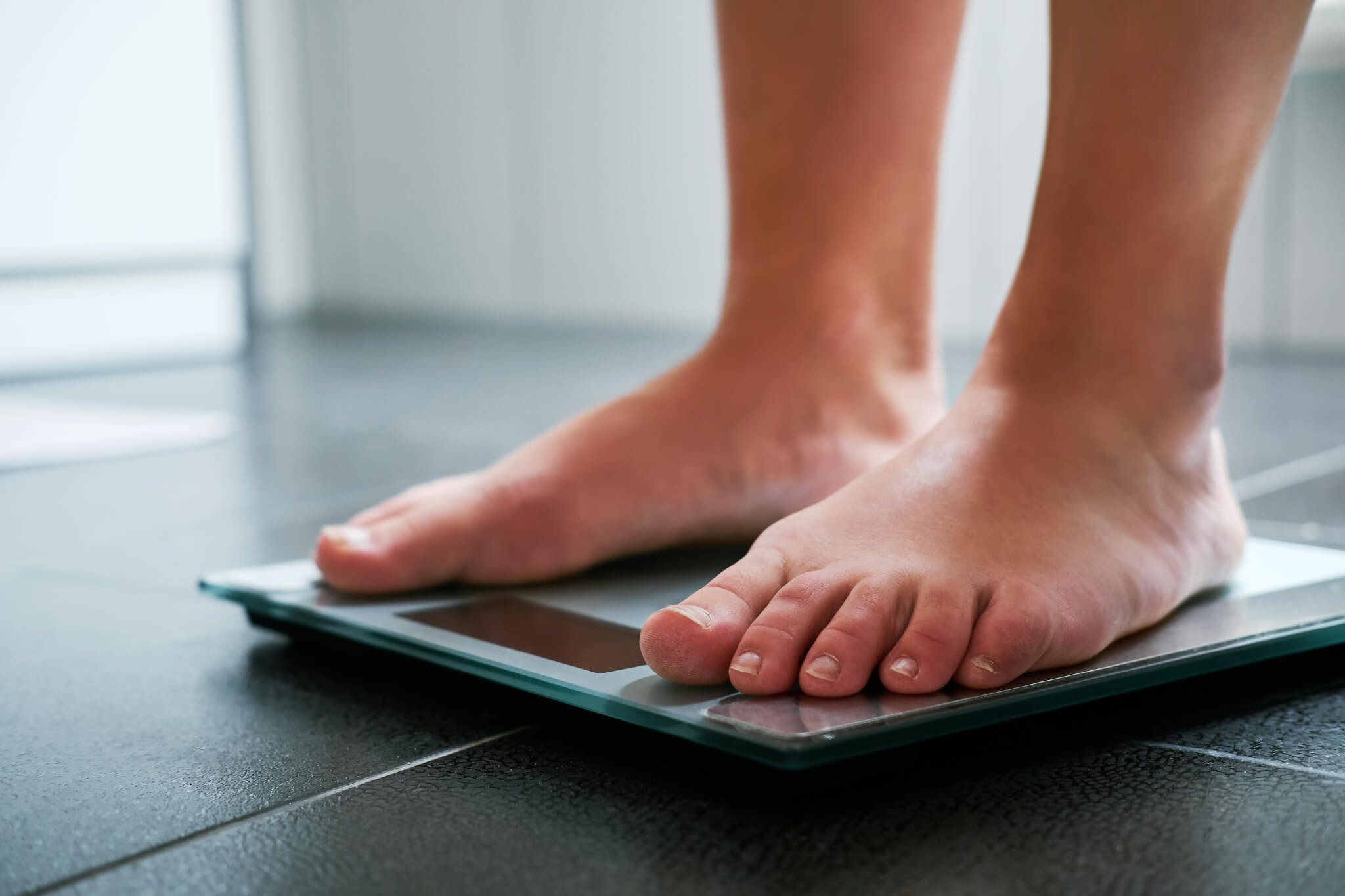 Female bare feet on the digital scale in the bathroom - Study Finds