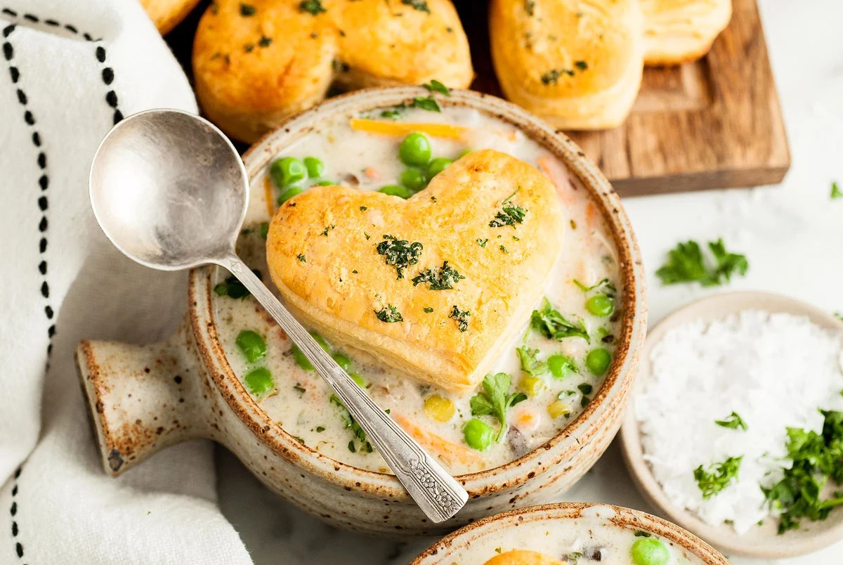 Chicken pot pie soup with a heart shaped biscuit on top.