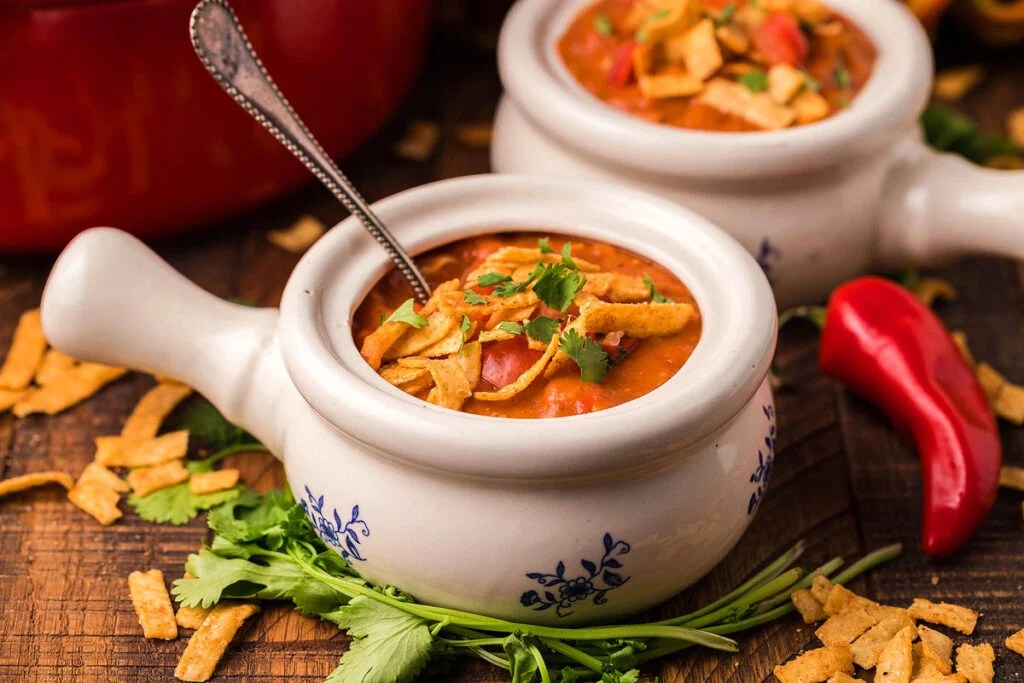 Homemade chicken enchilada soup in a white soup bowl with a handle.