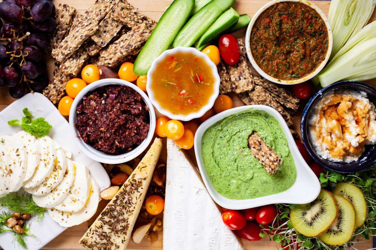 A platter of Italian appetizers, featuring a variety of vegetables and dips displayed on a wooden cutting board.
