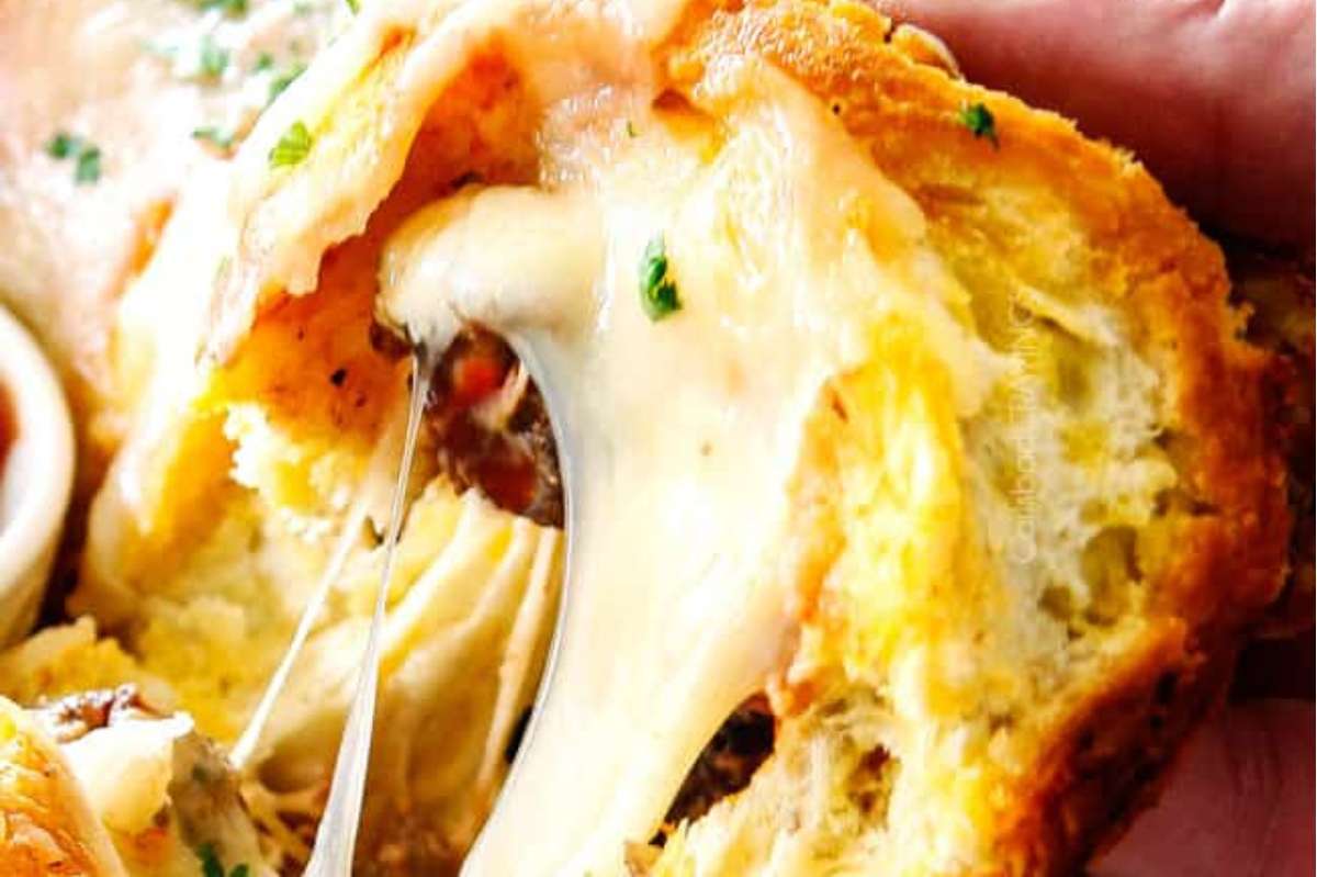 An Italian person savoring a bite out of a cheesy bread appetizer.