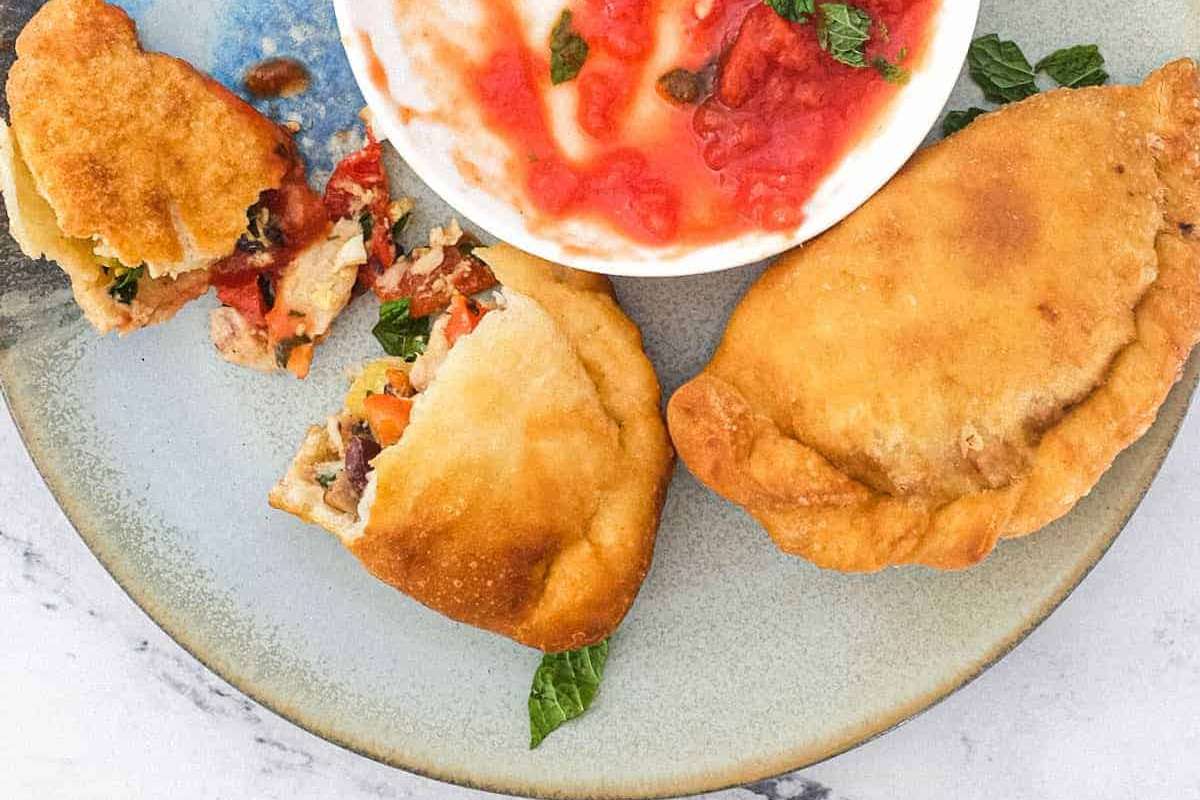 Two Italian empanadas served with dipping sauce, perfect as appetizers.