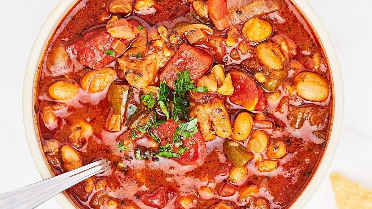 A bowl of chili with beans, tomatoes, and tortillas.