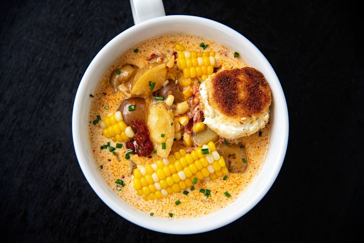 A tomato-based corn chowder with a biscuit on top.
