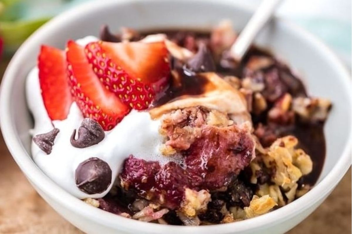 A bowl of strawberry chocolate chip cookie crumble with whipped cream.