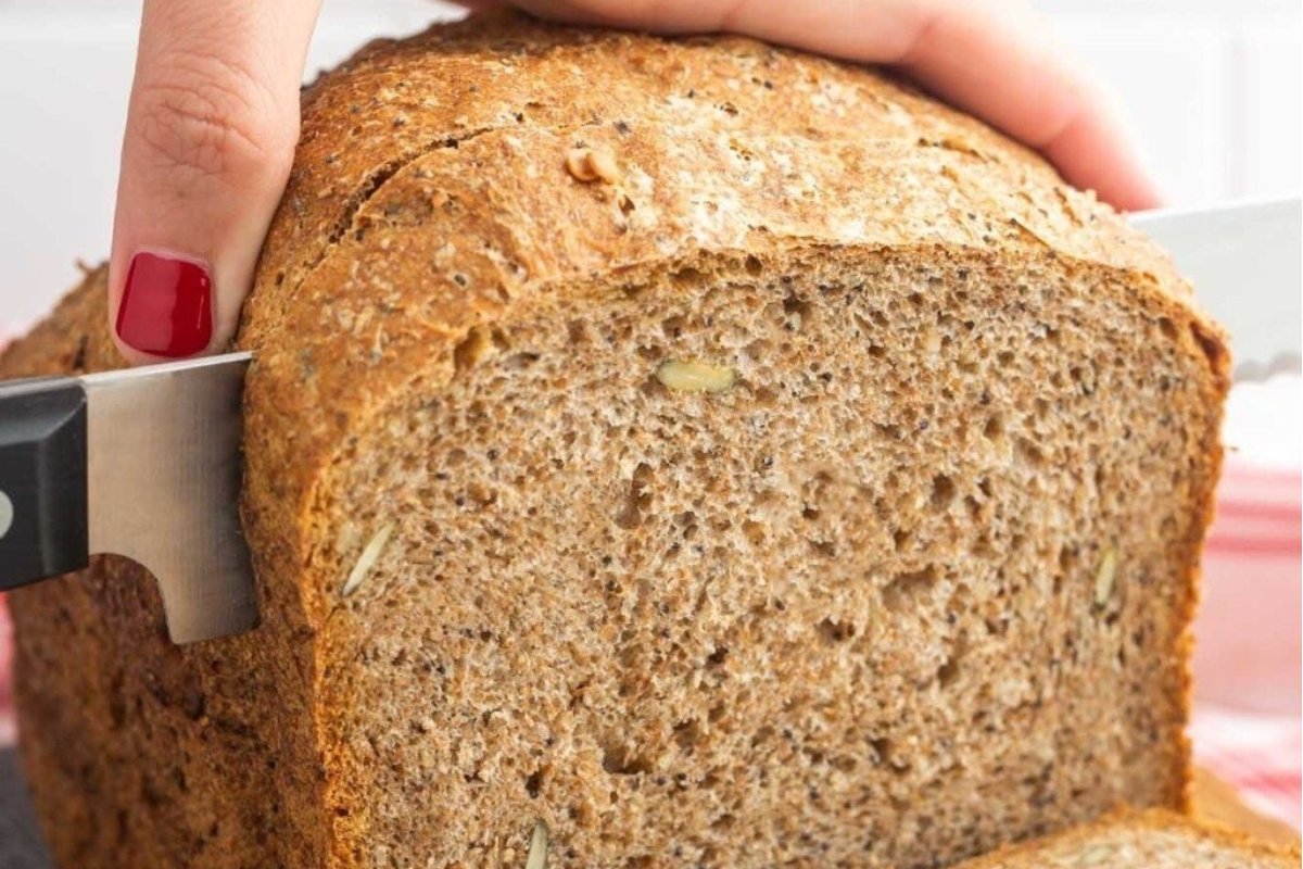 A person cutting a loaf of bread with a knife for bread recipes.