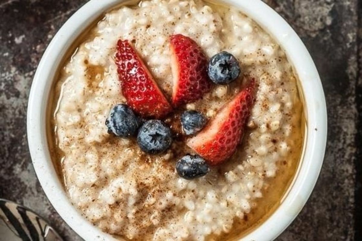 A bowl of oatmeal topped with fresh strawberries and blueberries.